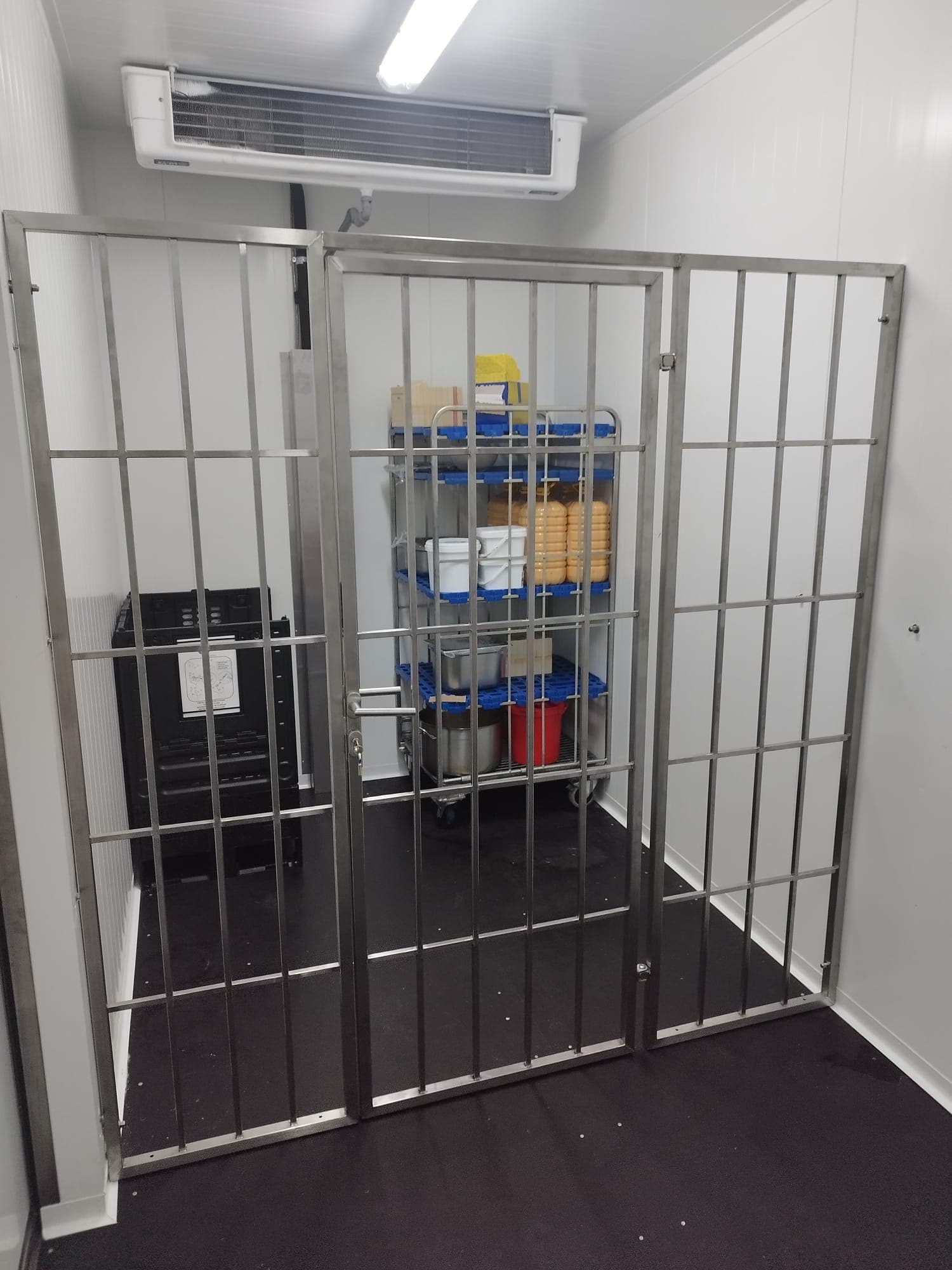 Nerezová mřížová dvoukřídlá brána v chladicí místnosti s regálem potravin